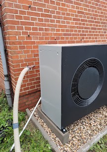 a black box with a round fan next to a brick wall, wärmepumpe